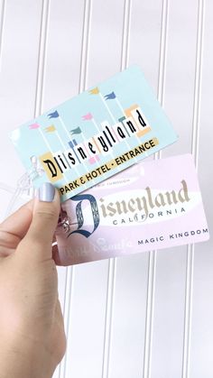 someone is holding up some disney land business cards with the word disneyland on them and there are other items in front of them