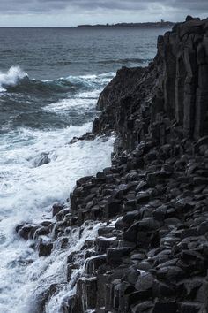 waves crashing against the rocky shoreline on an overcast day