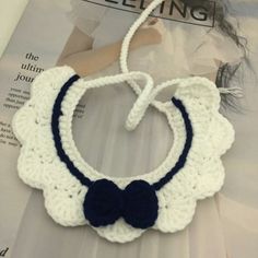 a crocheted necklace with a bow on it sitting on top of a magazine