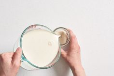 someone is pouring milk into a glass container