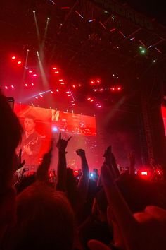 a crowd of people at a concert with their hands in the air and lights on