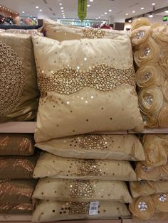 decorative pillows on display in a store for sale with gold sequins and beads