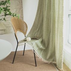 a chair sitting next to a window with a blanket on top of it and a potted plant in the corner