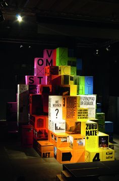 colorful boxes stacked on top of each other in an empty room with lights above them