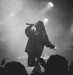 a man standing on top of a stage holding a microphone in front of a crowd