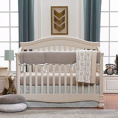 a baby crib in a room with blue and white curtains on the window sill