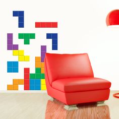 a red chair sitting in front of a white wall with colorful blocks painted on it