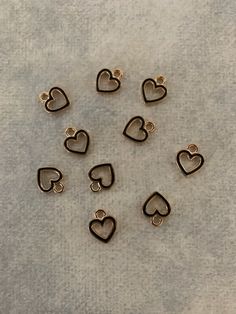 small heart shaped metal charms on a gray surface with gold colored trimmings and holes in the shape of hearts