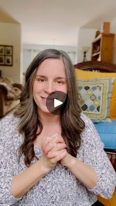 a woman standing in front of a couch holding her hands together