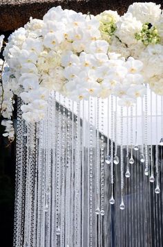 white flowers and chains hanging from the side of a building with water droplets on it