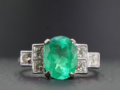 A beautifully  proportioned, bright and vibrant Colombian Emerald is the focal point of this sophisticated and artfully sculpted Gold and Diamond ring. This stunning ring boosts an oval 2.35 carat Colombian Emerald which is flanked by bright white high premium six princess cut sparkling Diamonds, totaling one carat. Quality;  H Colour,  Clarity:  VS1  The Diamonds sparkle and glisten with immense lustre. The Colombian Emerald is set in a secure classic four prong setting and displays a hue of li Gia Certified Oval Emerald Ring In Art Deco Style, Art Deco Oval Emerald Ring With Brilliant Cut, Luxury Oval Emerald Ring With Diamond Cut, Modern Gia Certified Oval Rings, Modern Oval Gia Certified Rings, White Gold Oval Emerald Ring Art Deco Style, Oval Emerald Ring With Diamond Cut In Platinum, Modern Oval Hallmarked Diamond Ring, Timeless Oval Diamond Cut Emerald Ring