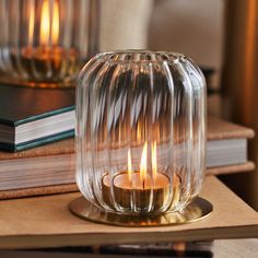 a clear glass candle holder sitting on top of a table next to a stack of books