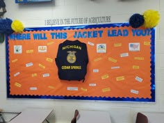 an orange and blue bulletin board with a jacket hanging from it's center wall