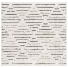 a white and grey rug with lines on the floor in front of a white wall