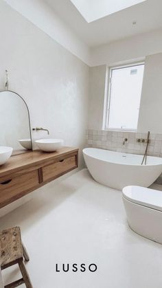 a white bathroom with two sinks and a bathtub next to a window that reads lusso