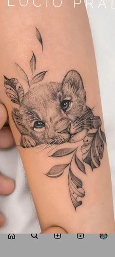 a woman's thigh with a tattoo of a lion and leaves on the side