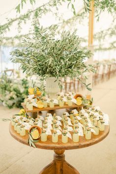 a table topped with cupcakes next to a potted plant and greenery