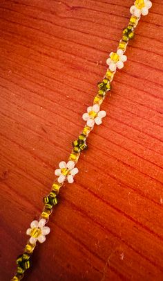 a close up of a wooden surface with flowers and beads attached to the end of it