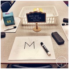 a white basket with writing on it next to a sign that says roll and write the letter m