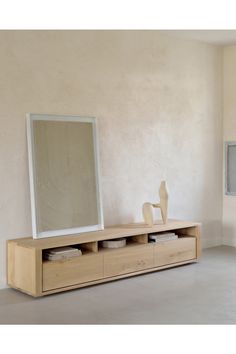 a white vase sitting on top of a wooden shelf next to a large framed mirror