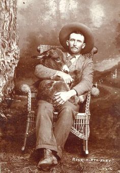 an old photo of a man sitting in a chair holding a cat