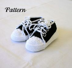 a pair of black and white crocheted shoes sitting on top of a bed