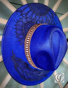 WEARING THE BLUES FEDORA Wide brim. Blue color custom hand burn fedora. Handmade. Adjustable inside ribbon. Comes as pictured. Item Details: Branded Wide Brim HatsEach hat is hand burned for a custom branded design, because of that each order will vary slightly. Hat band is included in the order. Please feel free to message me with any customization requests. These are quite literally completely customizable. Due to the custom nature of our hats, all purchases are nonreturnable and nonrefundable Handmade Blue Fedora With Curved Brim, Handmade Blue Fedora With Flat Brim, Handmade Blue Wide Brim Fedora, Artisan Blue Fedora With Short Brim, Handmade Blue Hat Bands With Curved Brim, Artisan Blue Wide Brim Fedora, Artisan Blue Flat Brim Fedora, Artisan Blue Fedora For Festivals, Custom Handmade Blue Hat Band