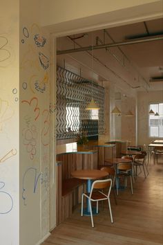 an empty restaurant with colorful graffiti on the wall and wooden tables in the foreground