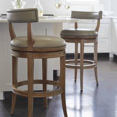 two brown stools sitting in front of a counter with wine glasses on top of it