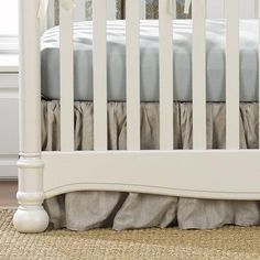 a white crib with ruffled bed skirt