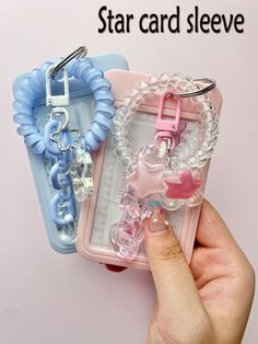 a hand holding two cell phones with charms attached to them