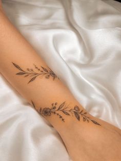 a woman's foot with tattoos on it laying on a white bed sheet,