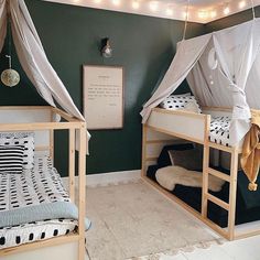 two bunk beds in a room with white curtains and lights on the wall above them