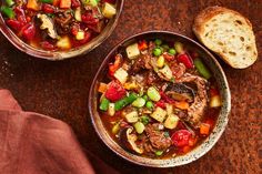 two bowls filled with stew next to a piece of bread