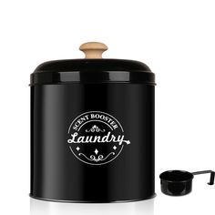 a black canister with a wooden lid and handle next to it is an empty cup