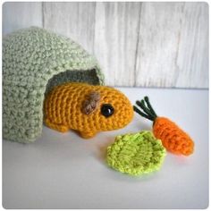 a crocheted stuffed animal with a carrot in it's mouth next to a knitted hat