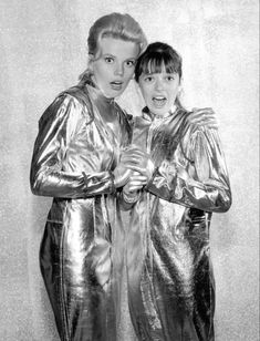 two women standing next to each other in shiny clothing