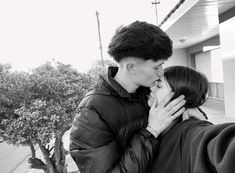 a man and woman kissing in front of a building