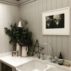 a white sink sitting under a mirror next to a potted plant on top of a counter