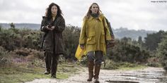 two women walking down a dirt road in the rain