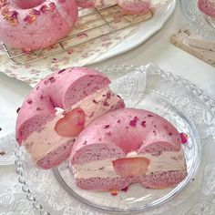 there is a pink donut with icing on the plate next to other pastries