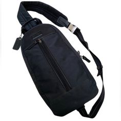 a black sling bag with an adjustable shoulder strap and zippered closures on the side