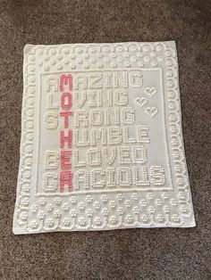 a crocheted afghan with the word mother written in red and white on it