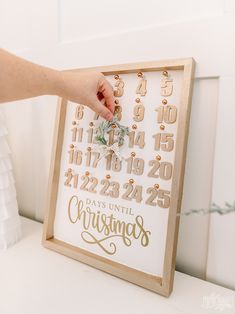 a person is holding a wooden frame with numbers on it and christmas decorations in front of them