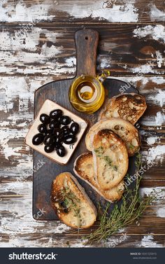 olives and bread are on a cutting board