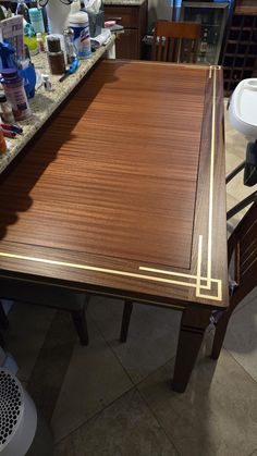 a wooden table sitting on top of a kitchen floor next to a sink and counter