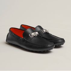 a pair of black loafers with red soles and metal buckles on them