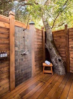 a wooden deck with a tree in the middle and a shower area on one side