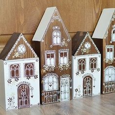 three small wooden houses sitting on top of a table next to each other with windows and doors