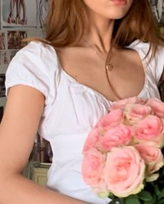 a woman holding a bouquet of pink roses